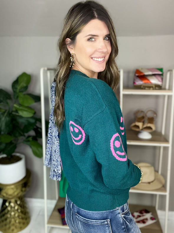 side view of teal sweater with pink smiley faces by THML 