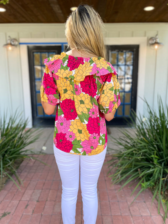 Back of pink, yellow, light pink floral top with white denim pants