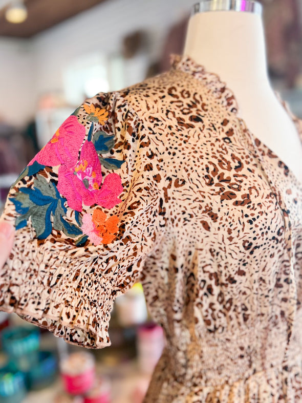 close up of floral embroidery on the sleeves of a leopard maxi dress