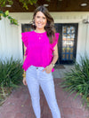 Magenta ruffle sleeve top styled with white denim pants 